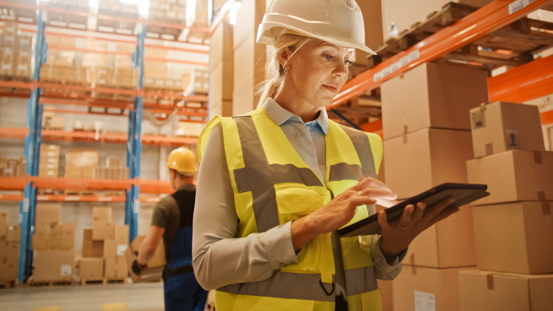 Womna wearing yellow safety hat  checking inventory in a warehouse