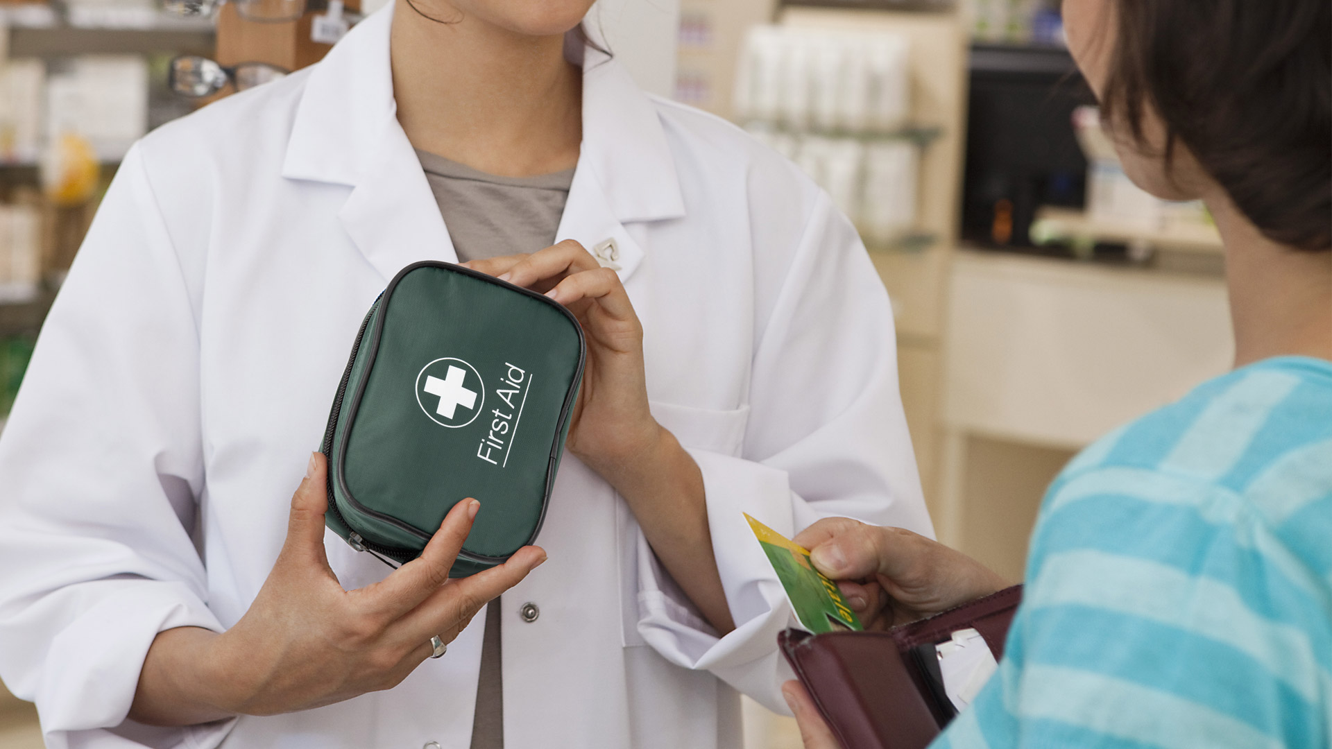 woman holding first aid kit and a person getting a card out of their wallet