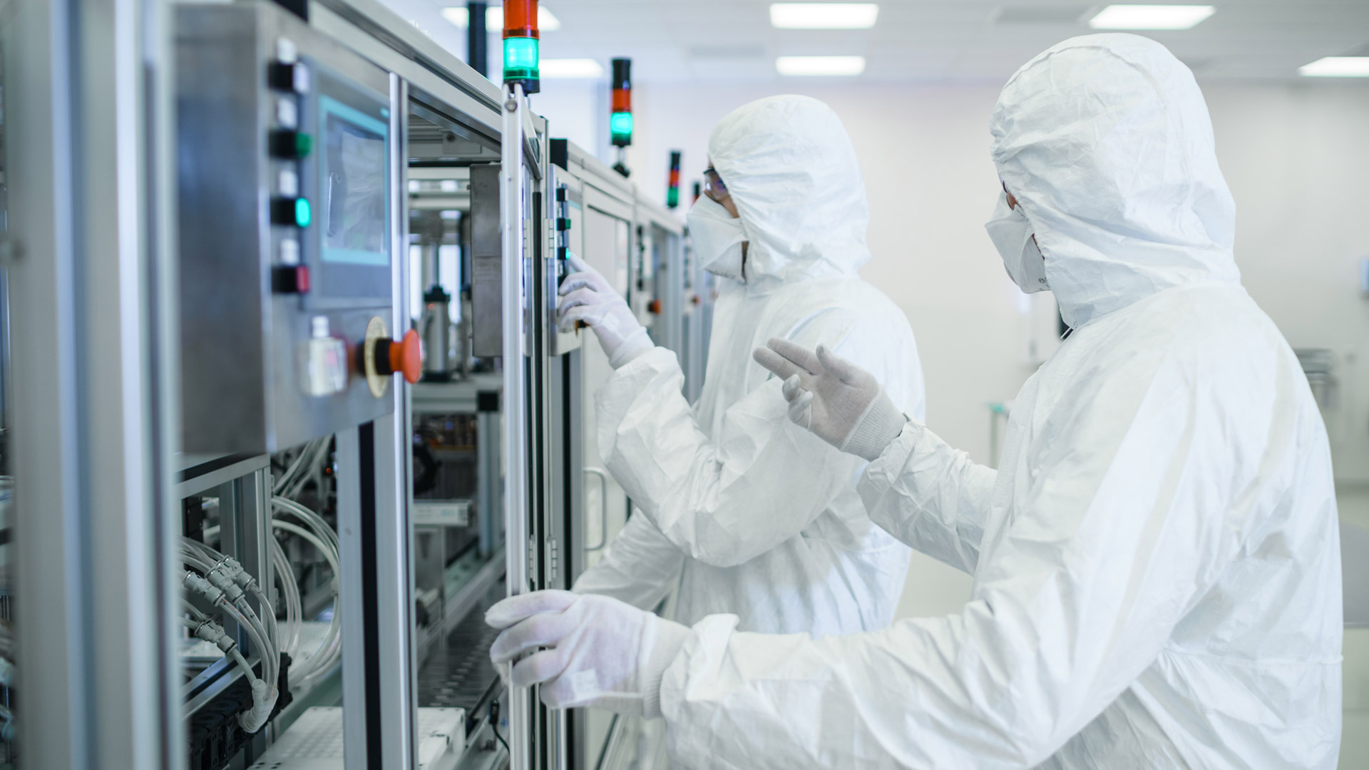 Two workers in Personal Protective Equipment working on a machine